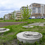 Fragment infrastruktury sanitarnej, wokół trawa, w tle bloki mieszkalne