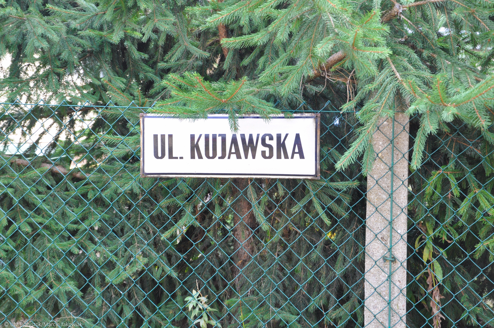 Tablica z nazwą ulicy zawieszona na ogrodzeniu