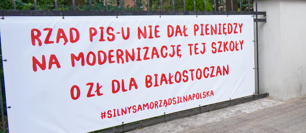 Baner z napisem: Rząd PIS-u nie dał pieniędzy na modernizację tej szkoły. 0 zł dla białostoczan. #silnysamorządsilnaPolska