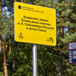 Żółta tablica informująca o ścieżce pieszo-rowerowej