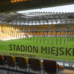Napis na szybie: Stadion Miejski w Białymstoku - w tle: murawa oraz trybuny