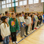 Uczniowie stoją w rzędach na sali gimnastycznej 