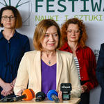 Kobieta przemawia, w tle zastępca prezydenta Przemysław Tuchliński wraz z uczestnikami wydarzenia
