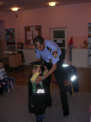 Strażnik miejski przebiera dziecko w wyposażenie Straży Miejskiej