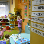 Dzieci podczas zabawy w przedszkolu oraz tabliczki z nazwami miesięcy na ścianie