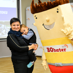 Mama z dzieckiem na rękach i maskotka Budżetu Obywatelskiego 2020
