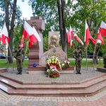 Żołnierze trzymający wartę przy Pomniku Katyńskim w Białymstoku, złożone wieńce oraz biało-czerwone flagi