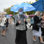 Wierni z parasolami i chorągiewkami w dłoniach podczas procesji