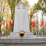 Flagi biało-czerwone i biało-żółto-czerwone oraz wieniec przy pomniku na Cmentarzu Wojskowym