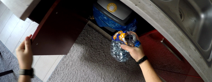 Mieszkaniec wyrzucający pustą butelkę do pojemnika na odpady