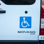 Niebieska naklejka na busie przedstawiająca wózek inwalidzki