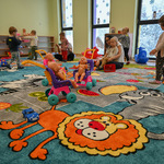 Motyw kolorowego lwa na dywanie i lalki w wózkach w sali zabaw
