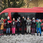 Dzieci stoją przed busem, w rękach trzymają kartki układające się w słowo Dziękujemy
