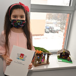 Dziewczynka-laureatka stoi przy swojej szopce bożonarodzeniowej