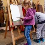 Dziewczynka maluje obraz na sztaludze