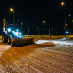 Maszyna spycha śnieg i odśnieża ulicę nocą