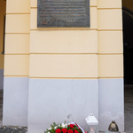 Znicze oraz kwiaty przed tablicą pamiątkową na budynku Kina Ton