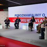 Organizatorzy oraz wszyscy uczestnicy debaty siedzący na tle multimedialnego panelu