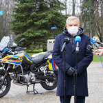 Prezydent Tadeusz Truskolaski przemawia do dziennikarzy, w tle: motocykl ratunkowy