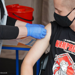 Medyk przykleja plaster na ramieniu mężczyzny po szczepieniu