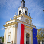 Brama pałacowa przyozdobiona flagami: Polski i Unii Europejskiej, widok boczny