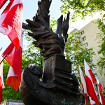 Pomnik przyozdobiony biało-czerwonymi flagami