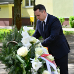 Zastępca prezydenta Przemysław Tuchliński poprawia kwiaty pod pomnikiem