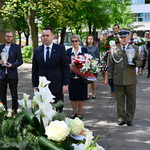 Zastępca prezydenta Przemysław Tuchliński pod pomnikiem, za nim stoją inni uczestnicy uroczystości