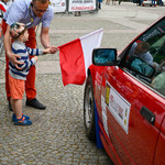 Chłopiec trzymający flagę przed autem rajdowym na linii startu
