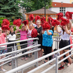 Uczennice trzymają czerwone pompony cheerleaderek
