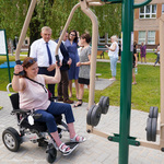 Kobieta na wózku ćwiczy na urządzeniu z siłowni plenerowej
