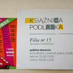 Tabliczka Książnicy Podlaskiej z godzinami otwarcia.
Poniedziałek, czwartek, piątek: 11.00 - 18.00. 
Wtorek: 11.00 - 19.00.
Sobota 10.00 - 15.00.