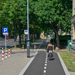 Rowerzystka jadąca ścieżką rowerową wzdłuż ulicy Kalinowskiego, w tle widać bujne kasztanowce