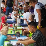 Mieszkańcy miasta wraz z dziećmi malujący przy stolikach