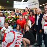 Olimpijczycy, osoby oczekujące na nich na lotnisku pozują do wspólnego zdjęcia