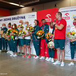Olimpijczycy pozujący do wspólnego zdjęcia na tle ścianki z logotypami sponsorów, do mikrofonu przemawia Wojciech Nowicki