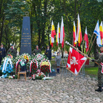 Pomnik Obrońców Getta ze złożonymi pod nim kwiatami, po prawej żołnierze oddają honory