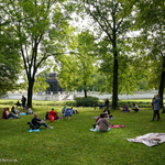 Ludzie siedzący na kocykach na trawie w parku