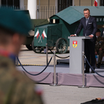 Zastępca Prezydenta Rafał Rudnicki przemawia na mównicy, w tle widać pojazdy wojskowe, w pierwszym planie żołnierze