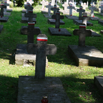 Groby żołnierzy na cmentarzu, przewiązane wstążką w barwach flagi Polski