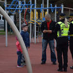 Dwie funkcjonariuszki Straży Miejskiej rozmawiające z mężczyzną i jego kilkuletnim synem na placu zabaw