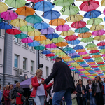 Tańcząca poddczas potańcówki pod kolorowymi parasolkami para