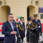 Zastępca Prezydenta Rafał Rudnicki przemawia do mikrofonu podczas uroczystości, w tle stoją Strażnicy Miejscy