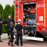 Strażacy prezentujący wóz strażacki dwóm chłopcom
