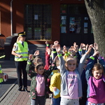 Na zdjęciu widoczne dzieci z elementami odblaskowymi stojące przed szkołą