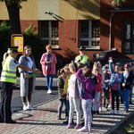Na zdjęciu dzieci wraz z elementami odblaskowymi stoją przed szkołą