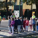 Na zdjęciu dzieci wraz z elementami odblaskowymi stoją przed szkołą