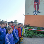 Uczniowie w strojach sportowych stoją koło szkoły