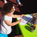 Kilkuletnia dziewczynka kolorująca kwiatki przy stoliku