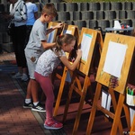 Dzieci malujące mazakami po kartkach przyczepionych do sztalug